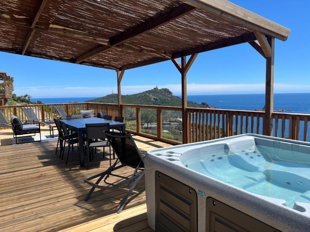 - un bain à remous sur une terrasse avec une table et des chaises dans l'établissement Mobilhome neuf Domaine 4 étoiles Ile d'Or terrasse et jacuzzi privé vue mer exceptionnelle, à Saint-Raphaël