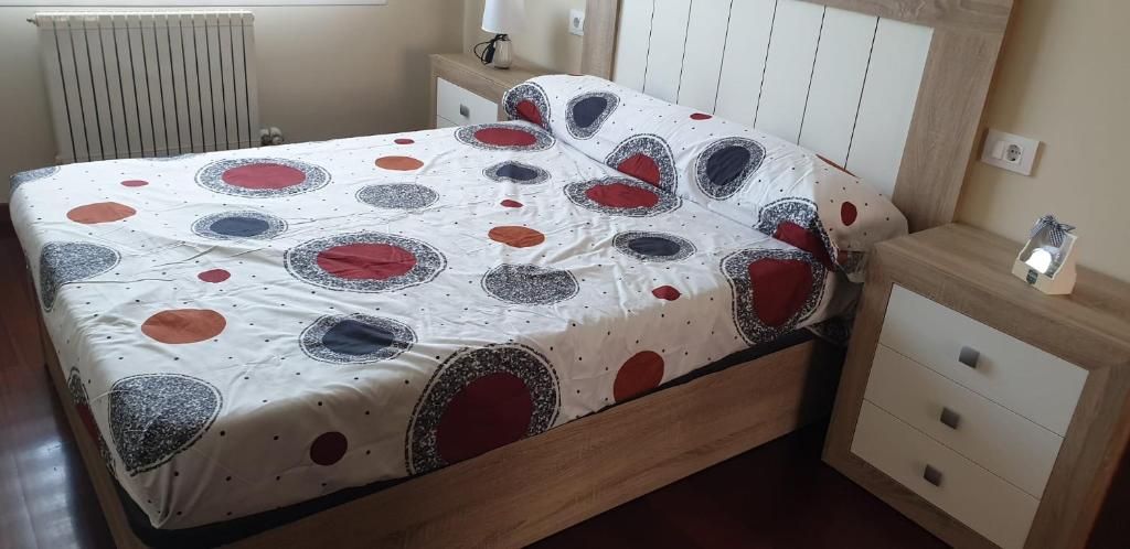 1 dormitorio con cama con colcha de lunares en Apartamento Avenida Constitución, en Boiro