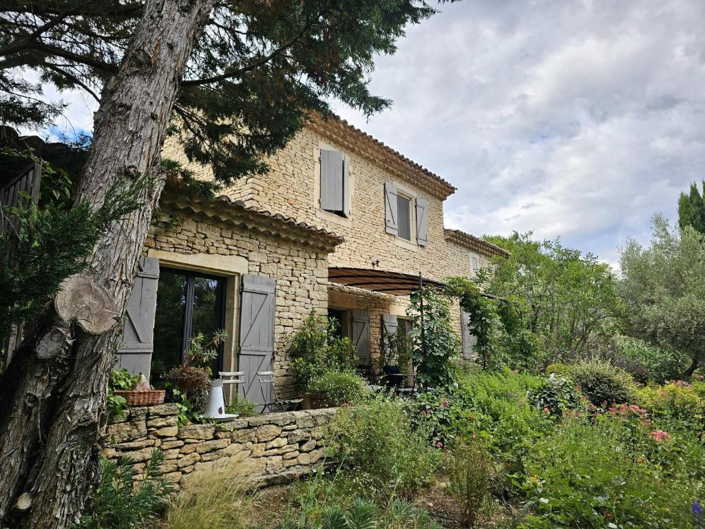 une maison en pierre avec un mur en pierre et un arbre dans l'établissement Superbe Mas Provençal avec piscine au pied de Gordes, à Gordes
