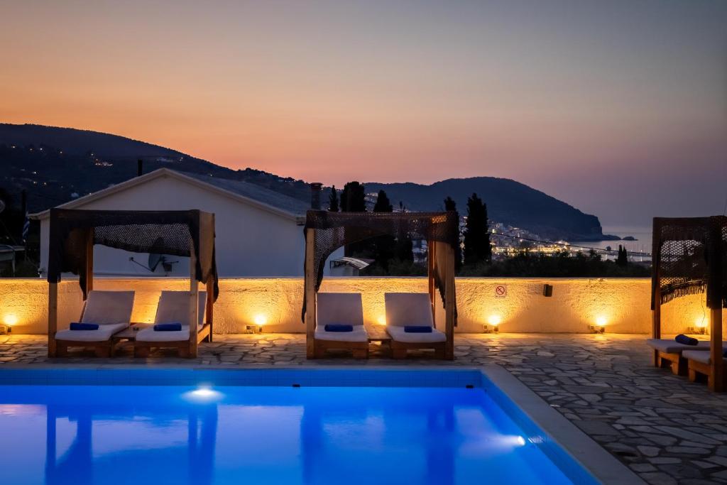 a swimming pool with two chairs and a tent at Skopelos Holidays Hotel & Spa in Skopelos Town