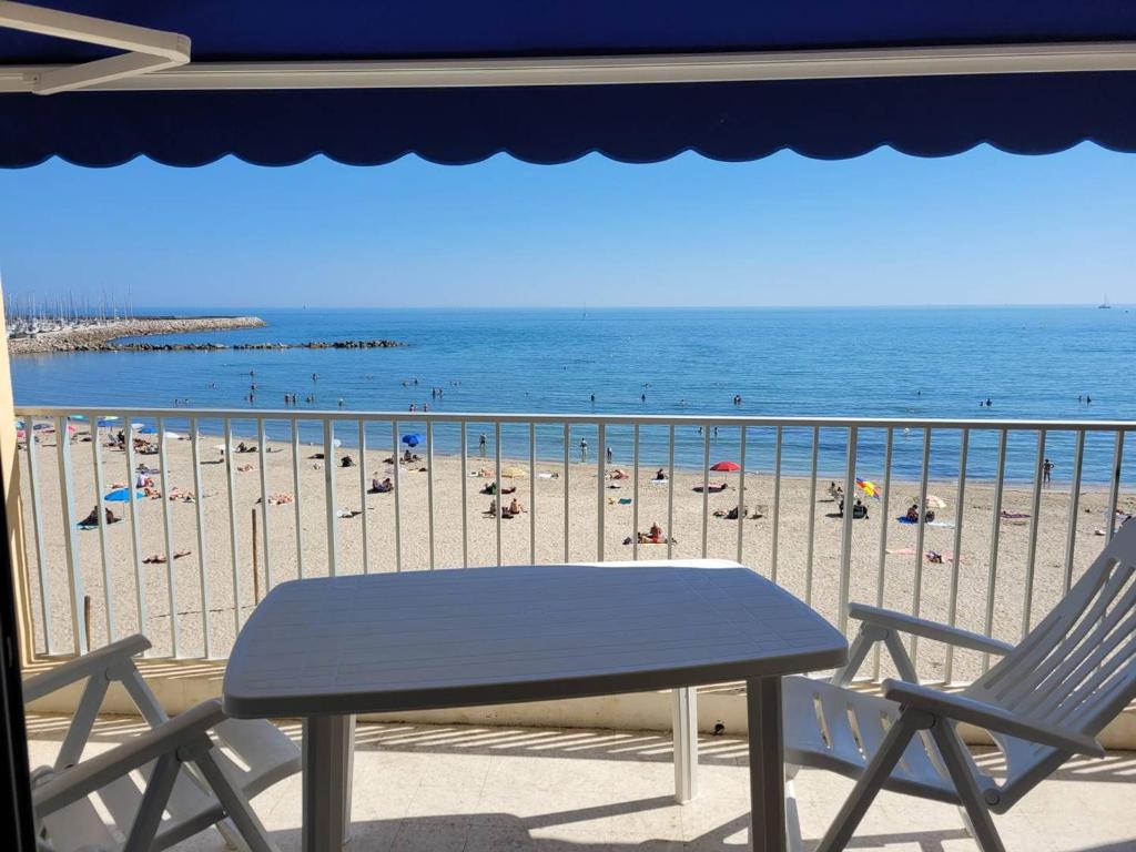 d'une table et de chaises sur un balcon avec une plage. dans l'établissement F3 à Palavas, en bord de mer, pour 4 personnes avec grande terrasse - FR-1-559-31, à Palavas-les-Flots