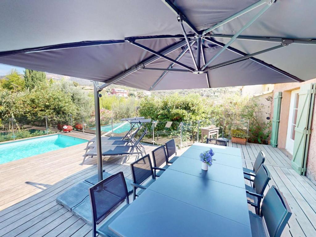 une table bleue et des chaises sous un parasol sur une terrasse dans l'établissement Belle villa climatisée avec piscine et parking au Lavandou - FR-1-308-200, au Lavandou