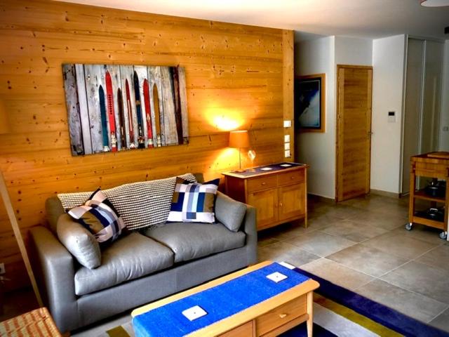 - un salon avec un canapé et un mur en bois dans l'établissement Appartement 4 personnes Bee on skis à Oz en Oisans, à Oz