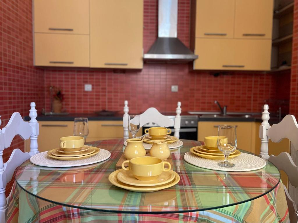 プレベザにあるOlga's houseのキッチンのテーブルに黄色いカップと皿が置かれている