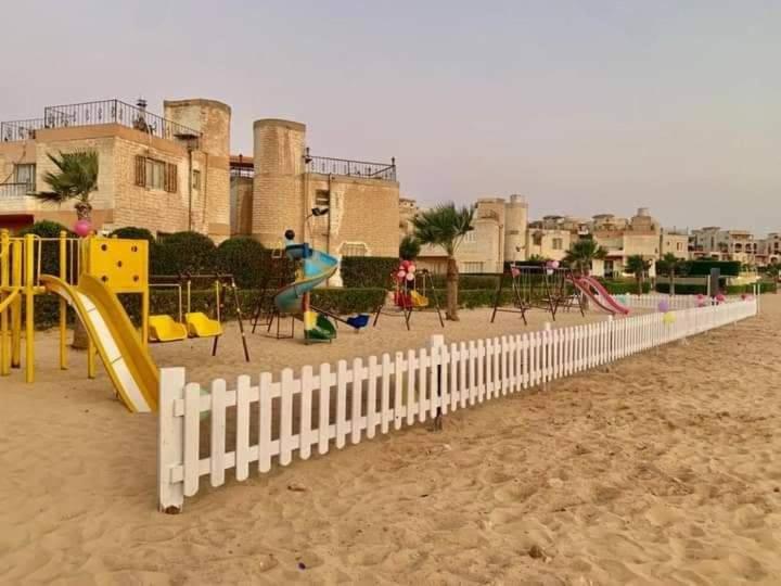 a playground with a white fence in the sand at شاليه علوى بالروف بقرية فينيسا باجمل شواطئ السخنه in Ain Sokhna
