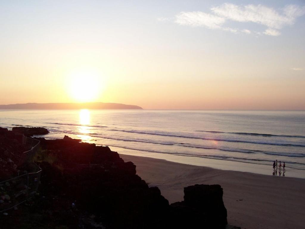 a sunset on a beach with the sun setting over the ocean at Ocean View in Castlerock