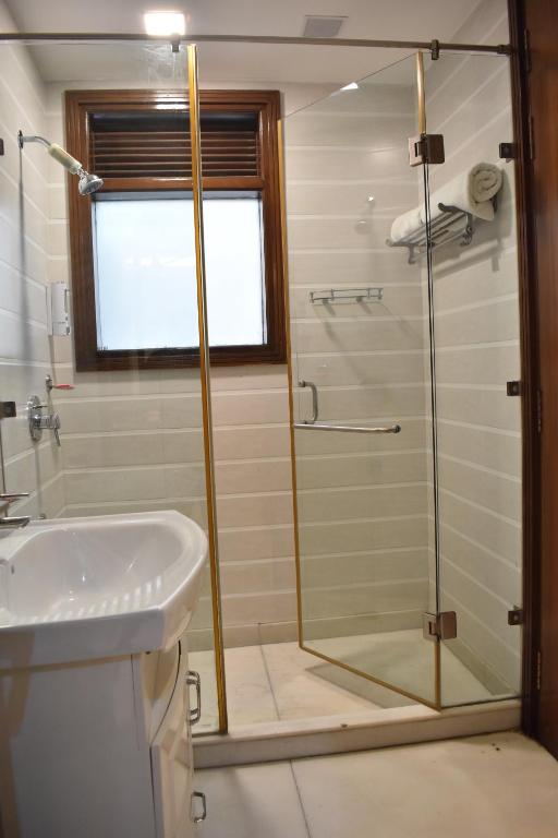 a bathroom with a glass shower and a sink at Two Green Park in New Delhi