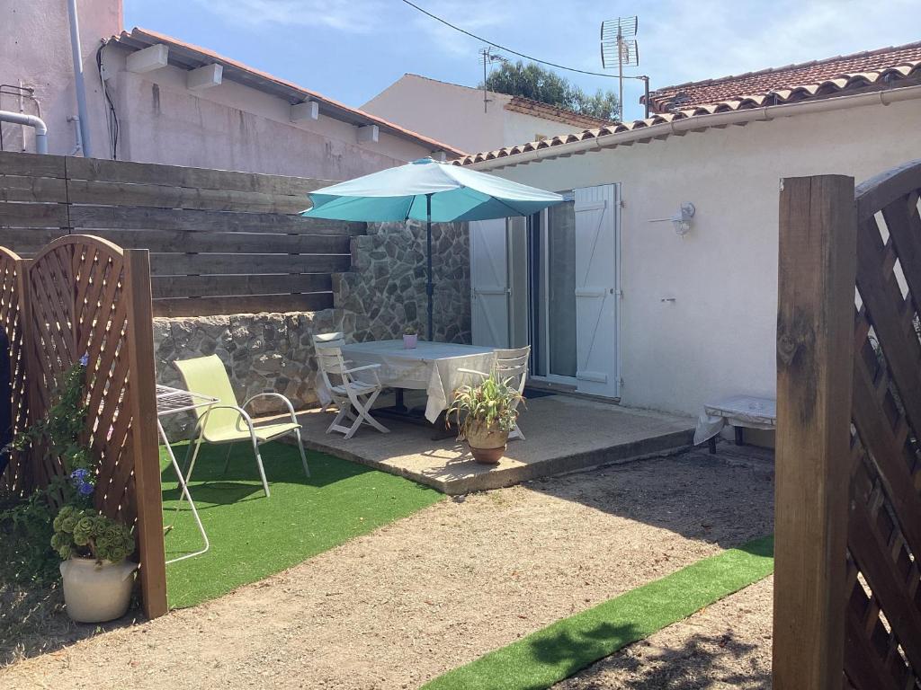 une terrasse avec une table et un parasol bleu dans l'établissement Appartement maisonnette de vacances, à Cannes