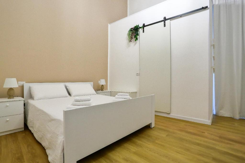 una camera con un letto bianco e una porta scorrevole di Elegante matrimoniale clemente house catania centro a Catania