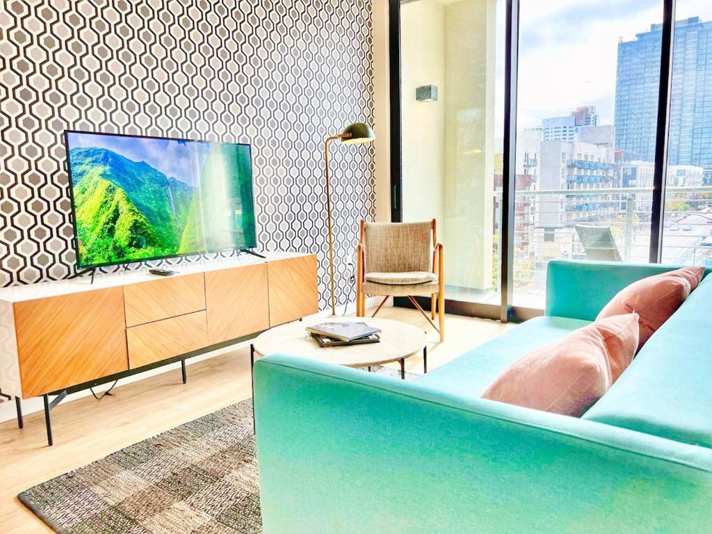 Una sala de estar con un sofá azul y un televisor. en Skyline Flat Facing Downtown San Diego, en San Diego