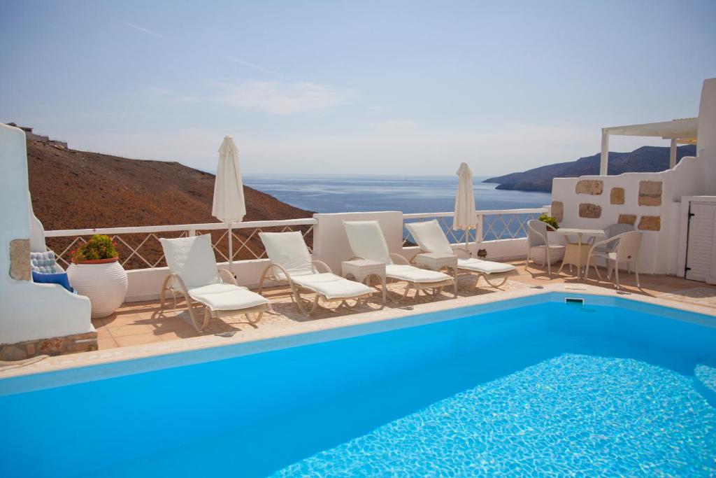a swimming pool with white chairs and a blue pool at Tholaria Boutique Hotel in Astypalaia