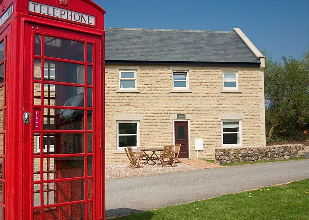 a red phone booth in front of a house at Farley in Matlock