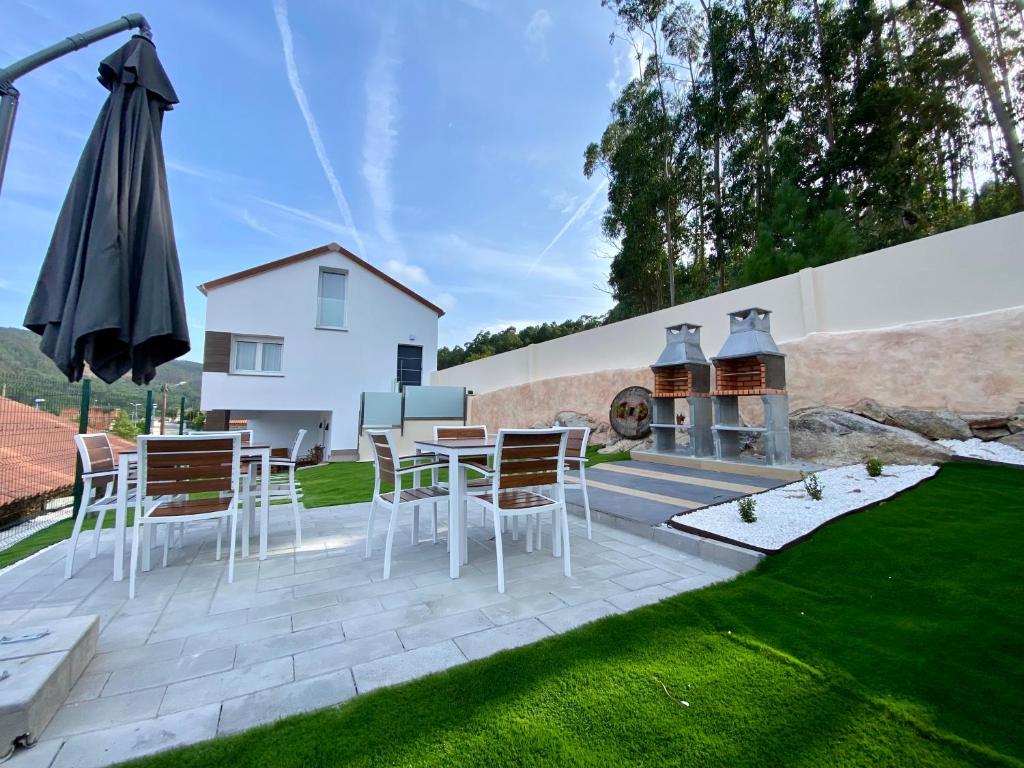 a patio with a table and chairs and an umbrella at Casa das Laixas in Laxe