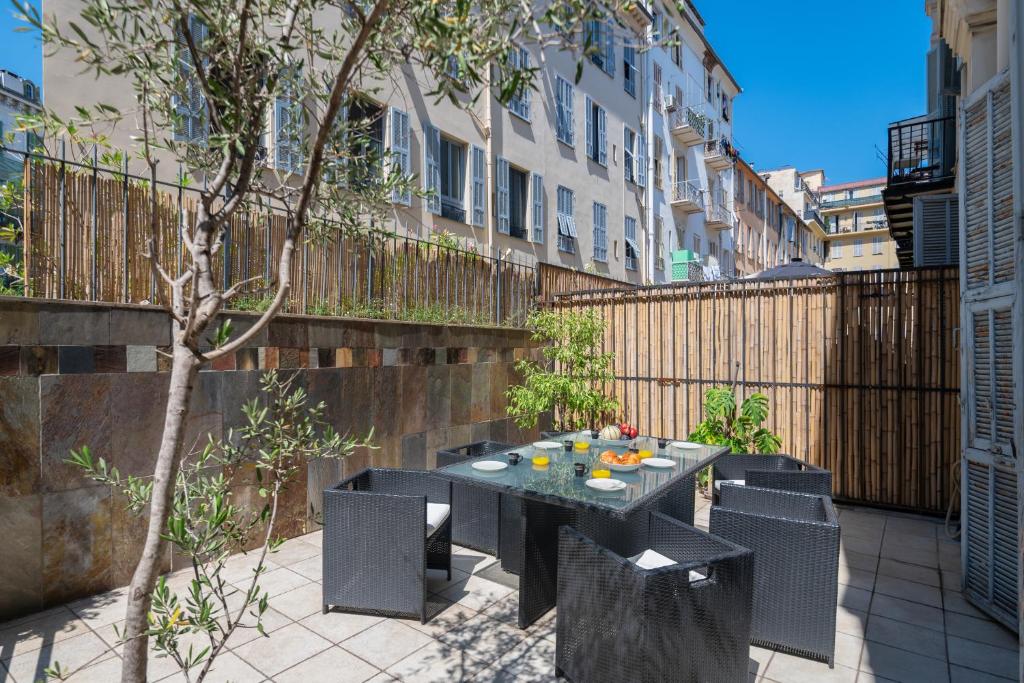 a patio with a table and chairs and a fence at "Le Zen" by EnjoyNice, central spacious apartment with Airco, beach at 10 min in Nice