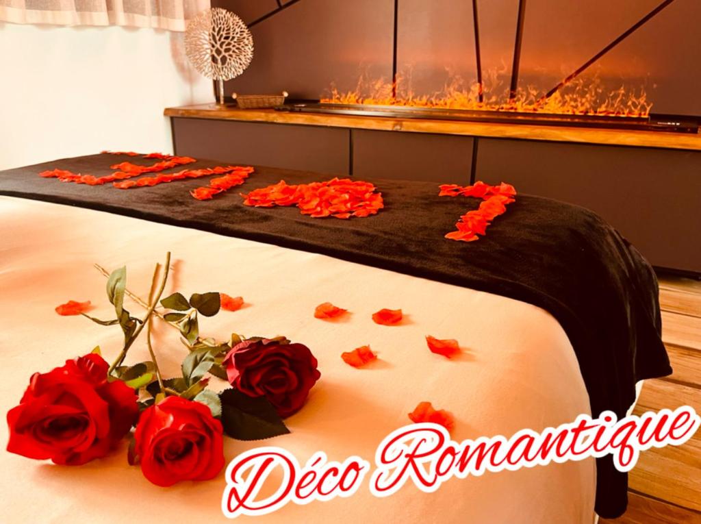 a bed with red roses on it with a fireplace at Cocon détente pour 2 avec hammam et jacuzzi privé Mer Lac in Le Barcarès