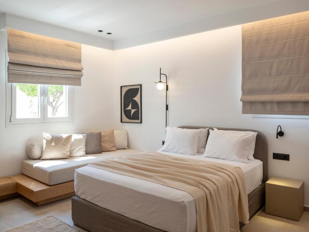 a white bedroom with a bed and a couch at Anemelia way of living in Naousa
