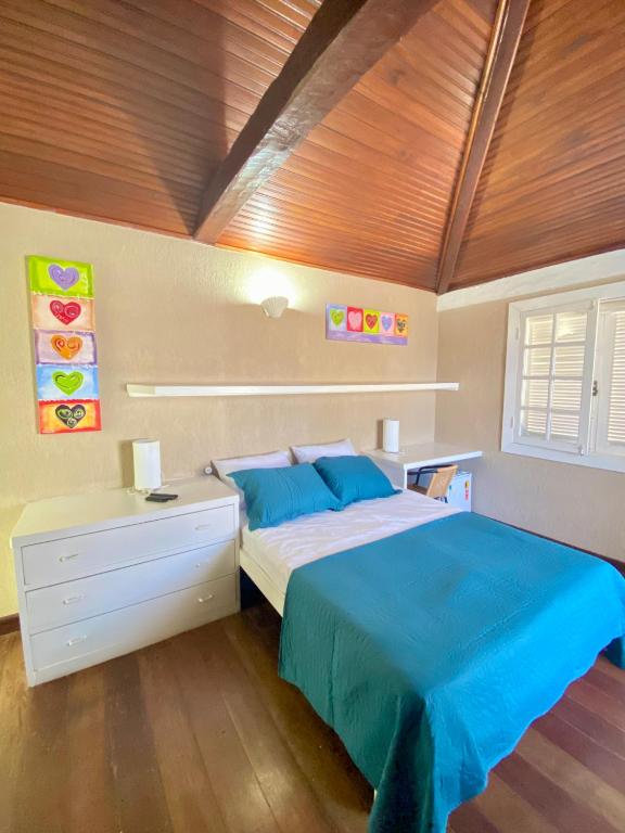 a bedroom with a bed with blue sheets and a wooden ceiling at Casa Dos Gringobz in Búzios