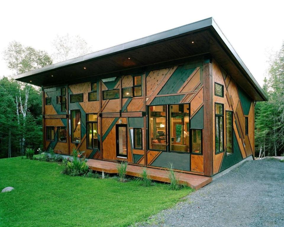 a house with a lot of windows on a field at Le Sculptural Spa, billiards, firepit & pool in Val-David