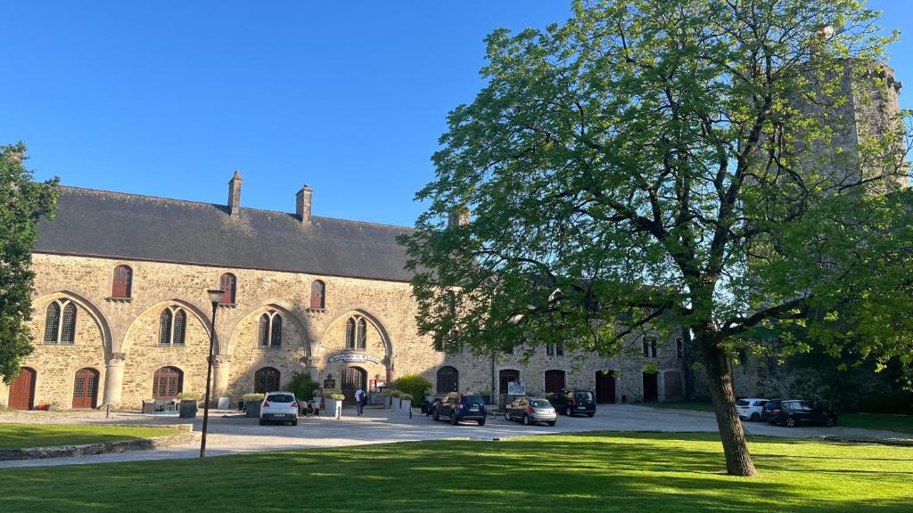 a large brick building with cars parked in front of it at L'Hostellerie du Château de Bricquebec in Bricquebec