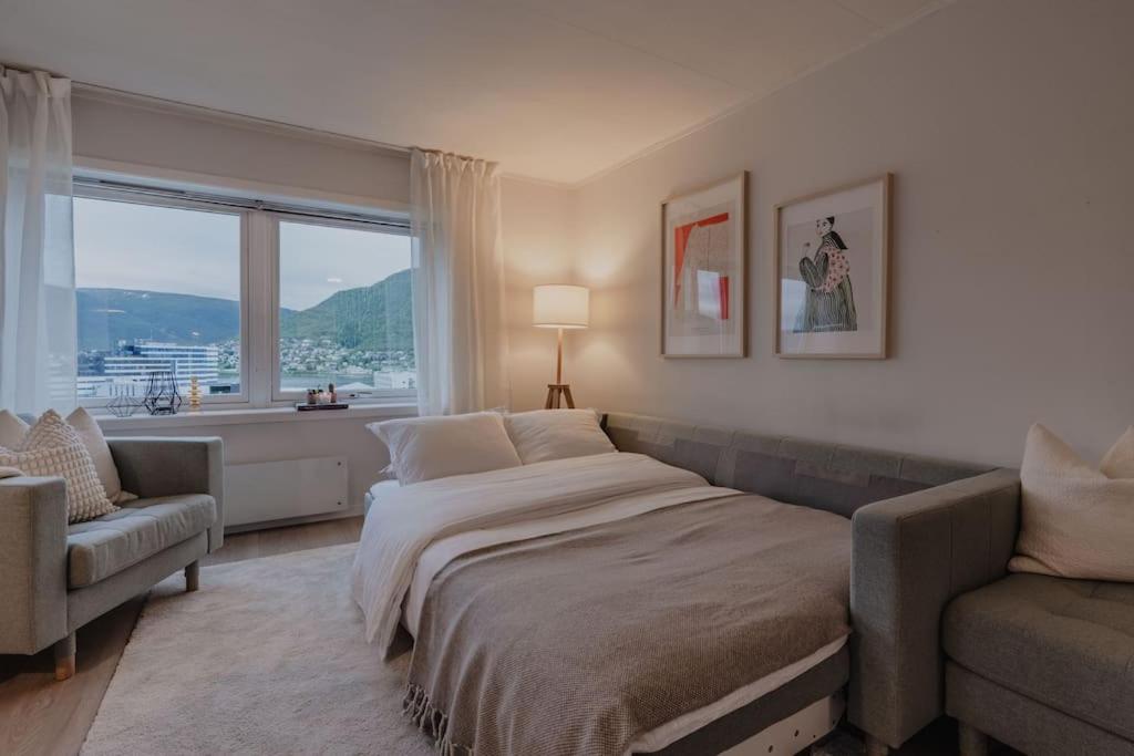 een slaapkamer met een bed, een bank en een raam bij Apartment in Tromsø City Centre in Tromsø