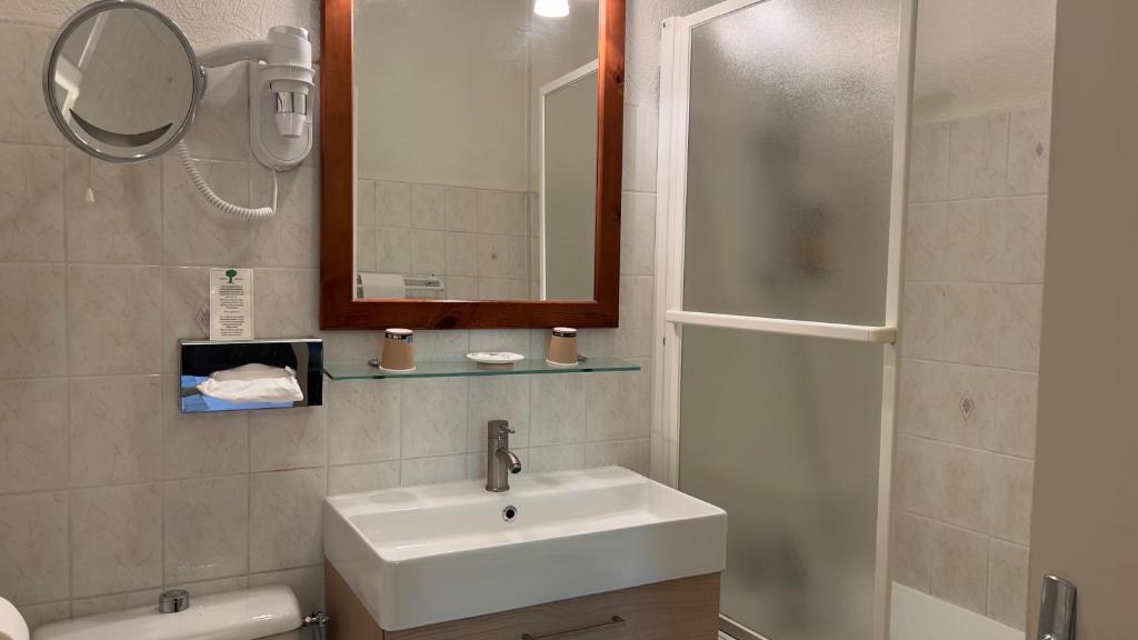 a bathroom with a sink and a mirror and a shower at L'Hostellerie du Château de Bricquebec in Bricquebec