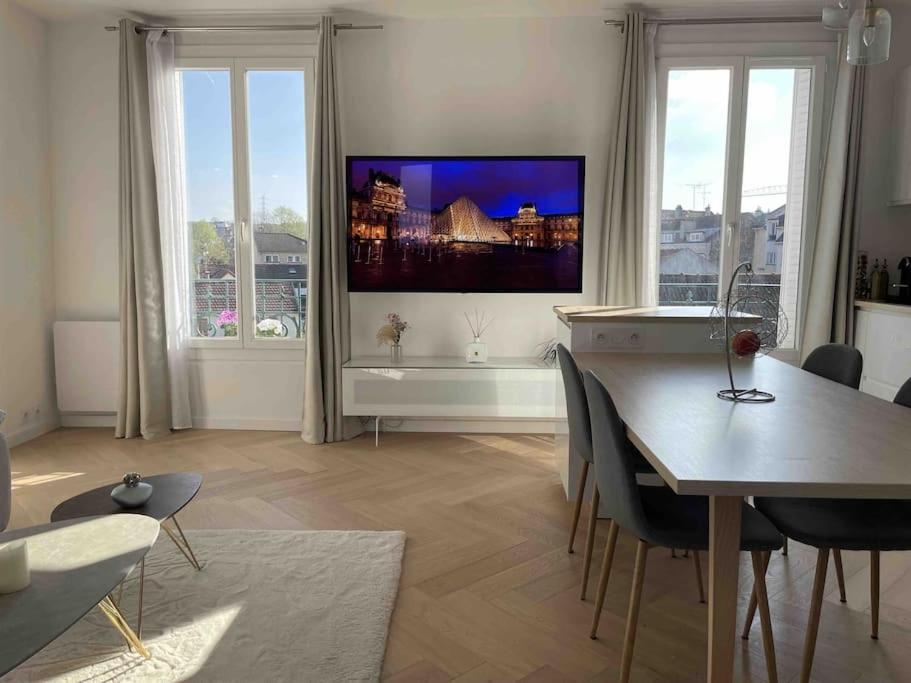 un salon avec une table et une télévision au mur dans l'établissement Superbe appartement lumineux et cosy proche Paris, à Villemomble