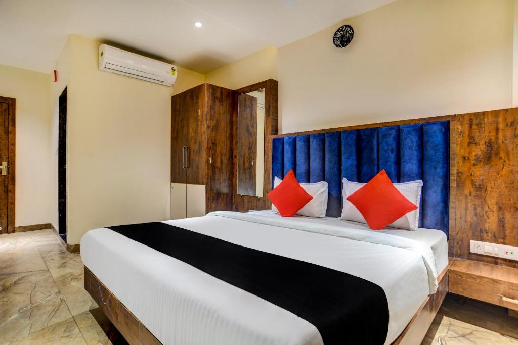 a bedroom with a large bed with red pillows at Capital O Abri Krishna in Indore