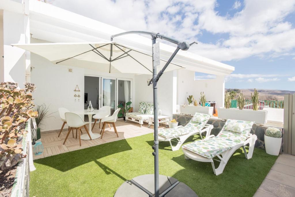 eine Terrasse mit einem weißen Sonnenschirm, Stühlen und einem Tisch in der Unterkunft Playa del Aguila Bungalow con Terraza Solarium in Maspalomas