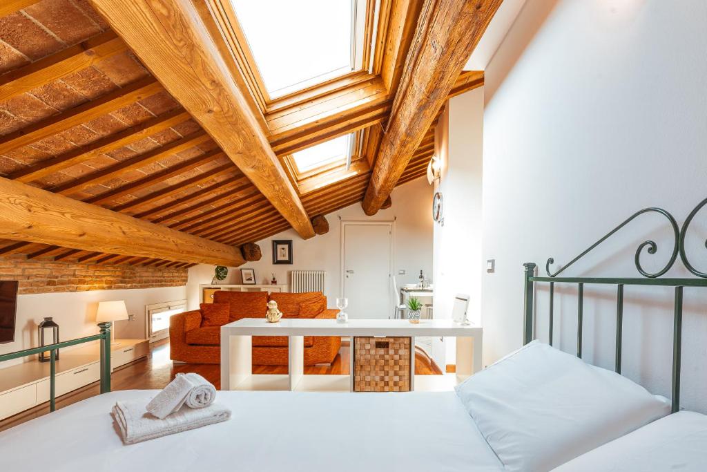 Un dormitorio con una cama y una sala de estar. en Mansarda Magellano - Parcheggio Auto, en Ferrara