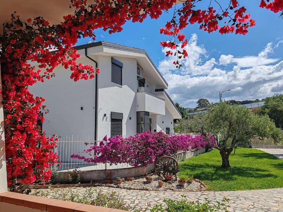 ein weißes Gebäude mit roten Blumen davor in der Unterkunft Eco Appartamento Mediterraneo in Catanzaro