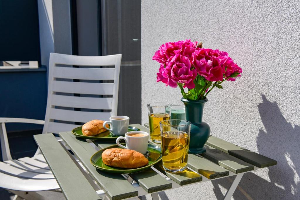 a table with two plates of food and a vase of flowers at Rosemary Apartment in Bratislava
