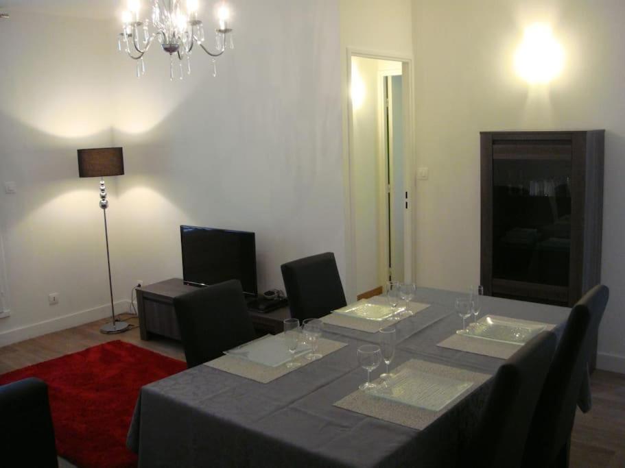 une salle à manger avec une table, des chaises et un lustre dans l'établissement L'appartement du Lys, à Périgueux