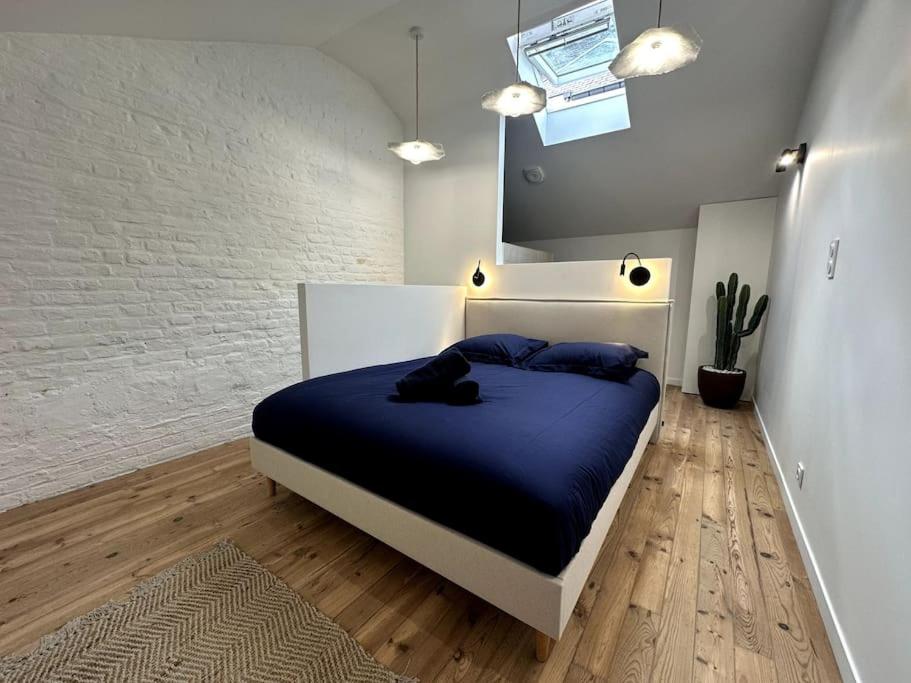 une chambre avec un lit avec des draps bleus et un miroir dans l'établissement Gare Unique Duplex lumineux, à Amiens