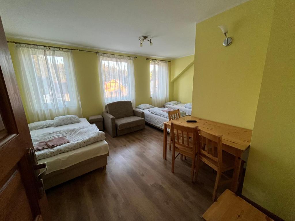 a room with two beds and a desk and a table at Pokoje REMUS in Szymbark