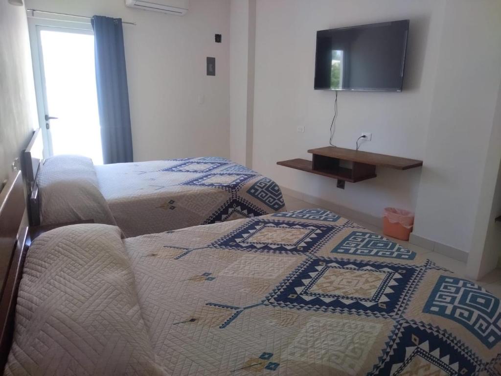 a bedroom with two beds and a tv on the wall at HOTEL PLAZA in La Paz