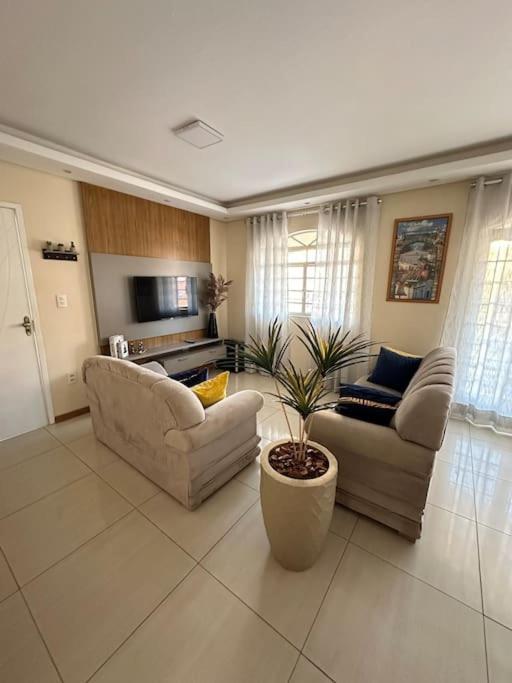 a living room with two couches and a plant at Linda casa pertinho de Tiradentes in São João del Rei