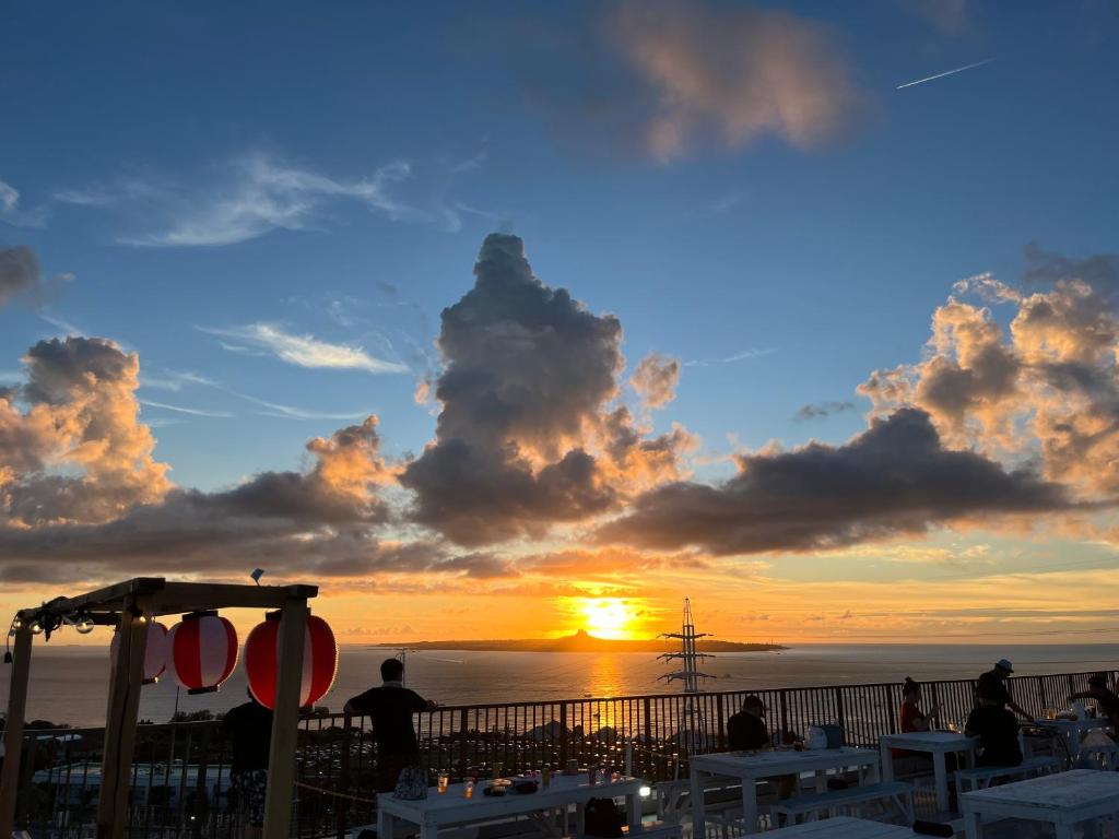 a sunset on the beach with people watching the sun set at Yukurina Resort Okinawa in Motobu