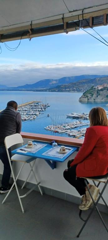 a man and woman sitting at a table with a view of a harbor at B&B Il Convento in Agropoli
