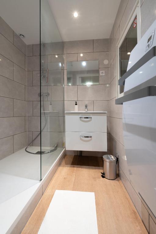 une salle de bain avec un lavabo et une douche en verre dans l'établissement 55m2 cosy au calme avec terrasse et box individuel, à Nouzonville
