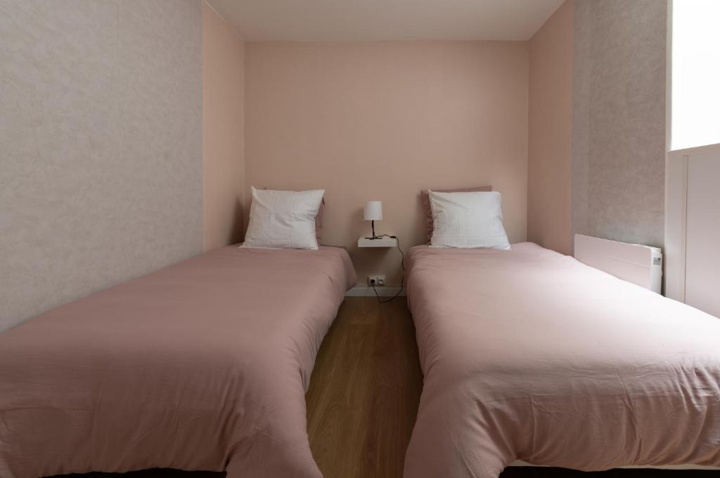 two beds sitting next to each other in a room at 55m2 cosy au calme avec terrasse et box individuel in Nouzonville
