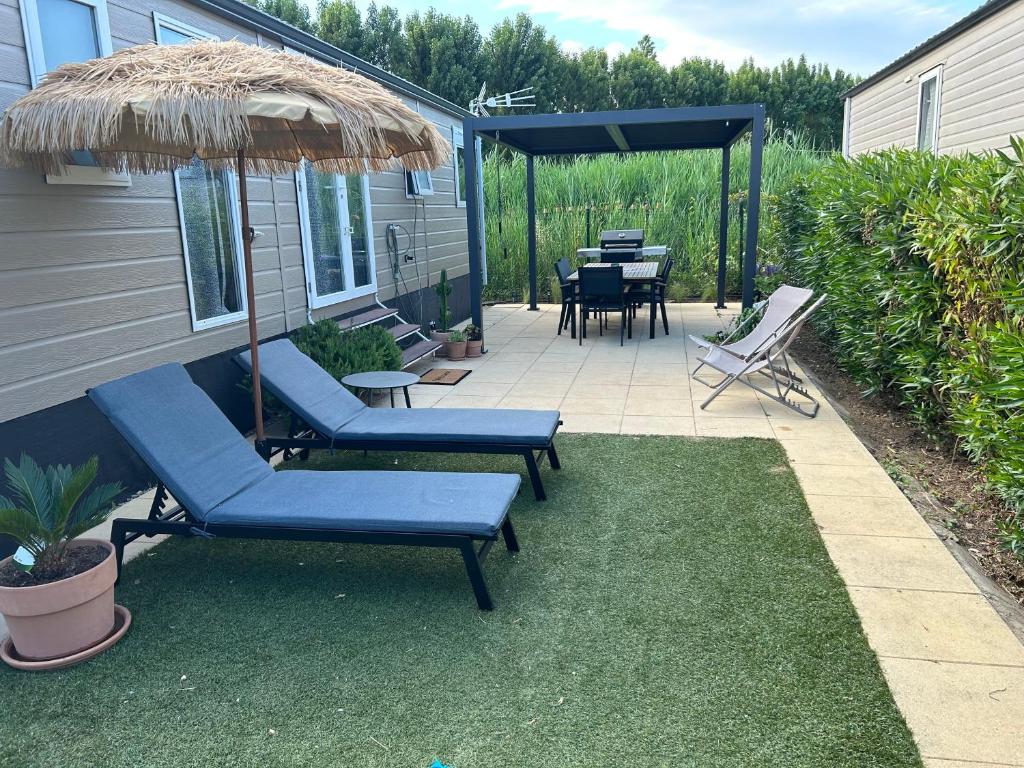 une terrasse avec des chaises, un parasol et une table dans l'établissement Bungalow Port Grimaud 177, à Grimaud