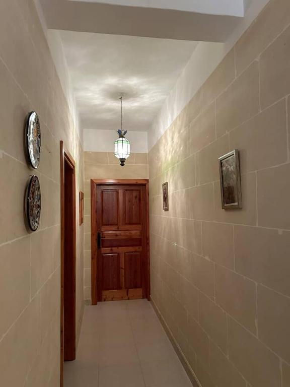 an empty hallway with a wooden door and a light at An excellent getaway choice, in the midst of Qbajjar and Marsalforn Bay! in Żebbuġ