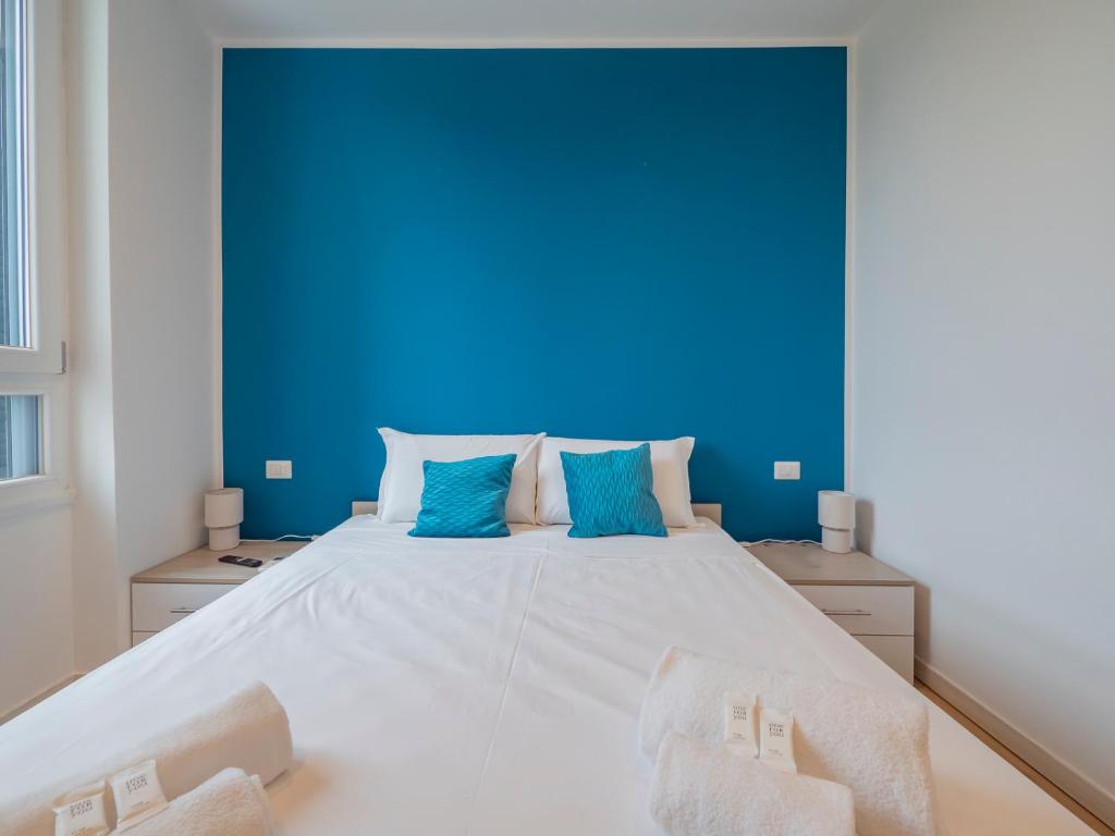 Hotel I Host Apartment - Rogoredo 49, a bedroom with a large white bed with blue walls at I Host Apartment - Rogoredo 49 in Milan