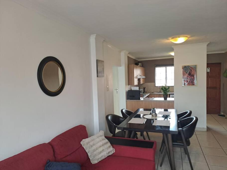 a living room with a red couch and a table at Naomi's Place at Stone Arch in Germiston