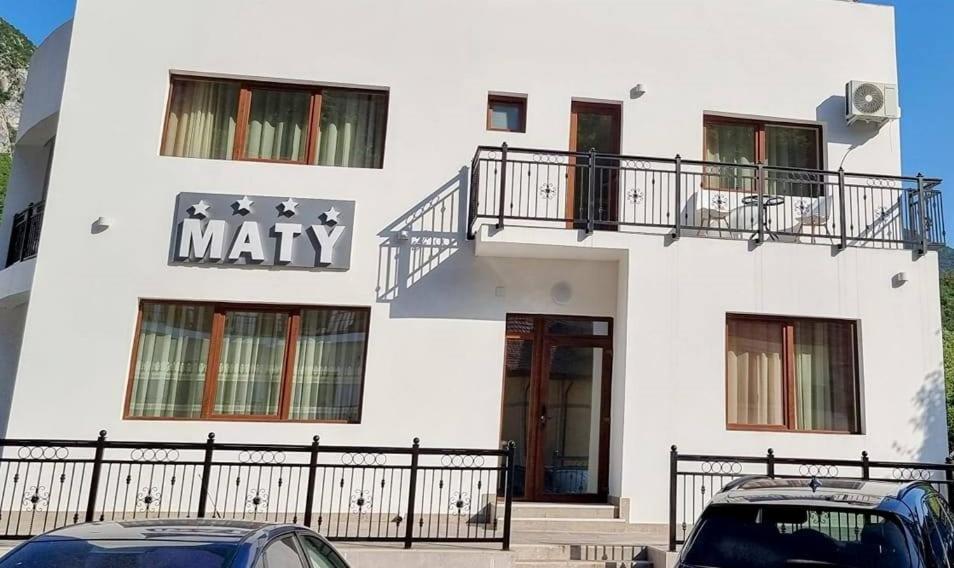two cars parked in front of a white building at Pensiunea Maty in Băile Herculane