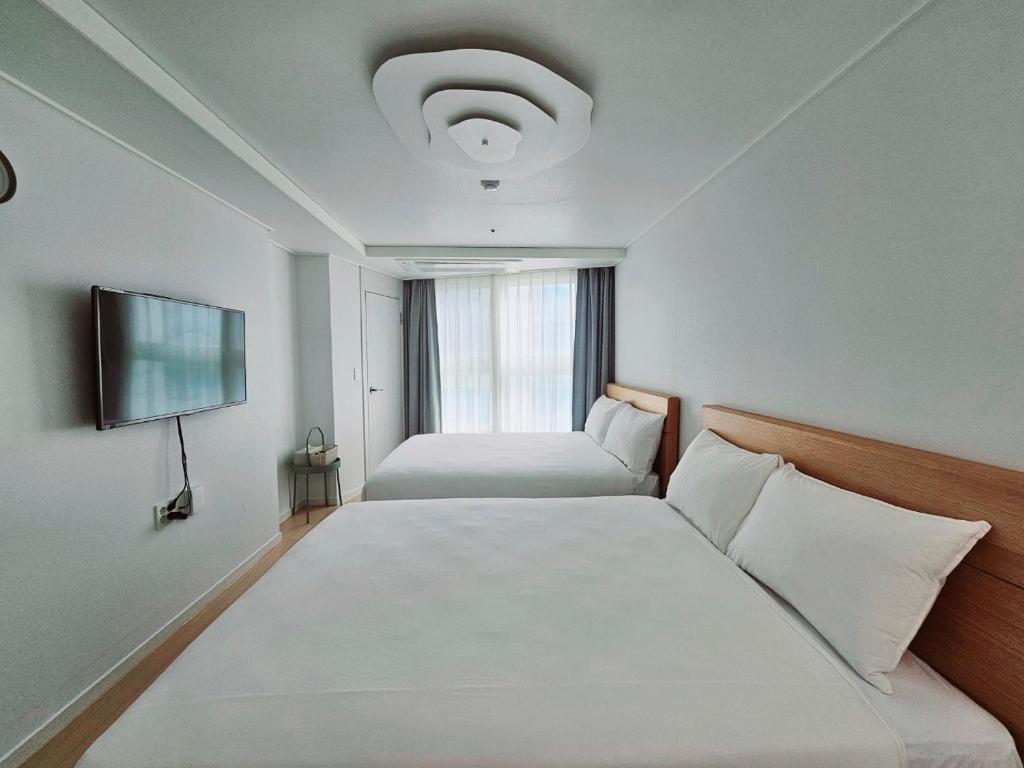 釜山にあるCiel de Merのベッド2台と薄型テレビ付きのホテルの部屋