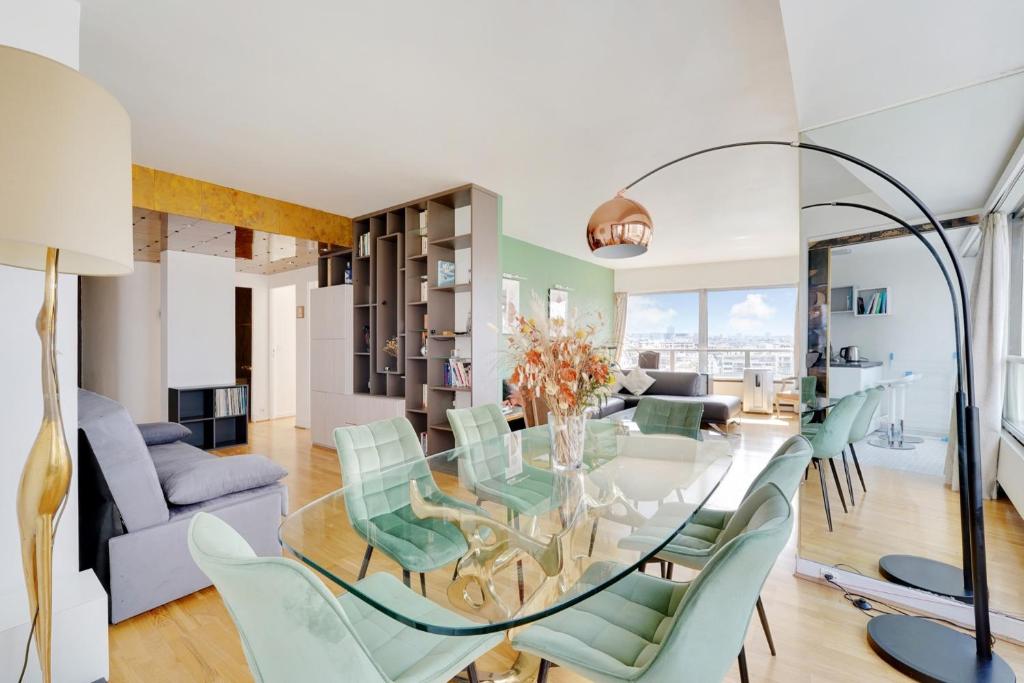 une salle à manger avec une table en verre et des chaises vertes dans l'établissement Seine & Eiffel 100m2 avec vue panoramique parking, à Paris