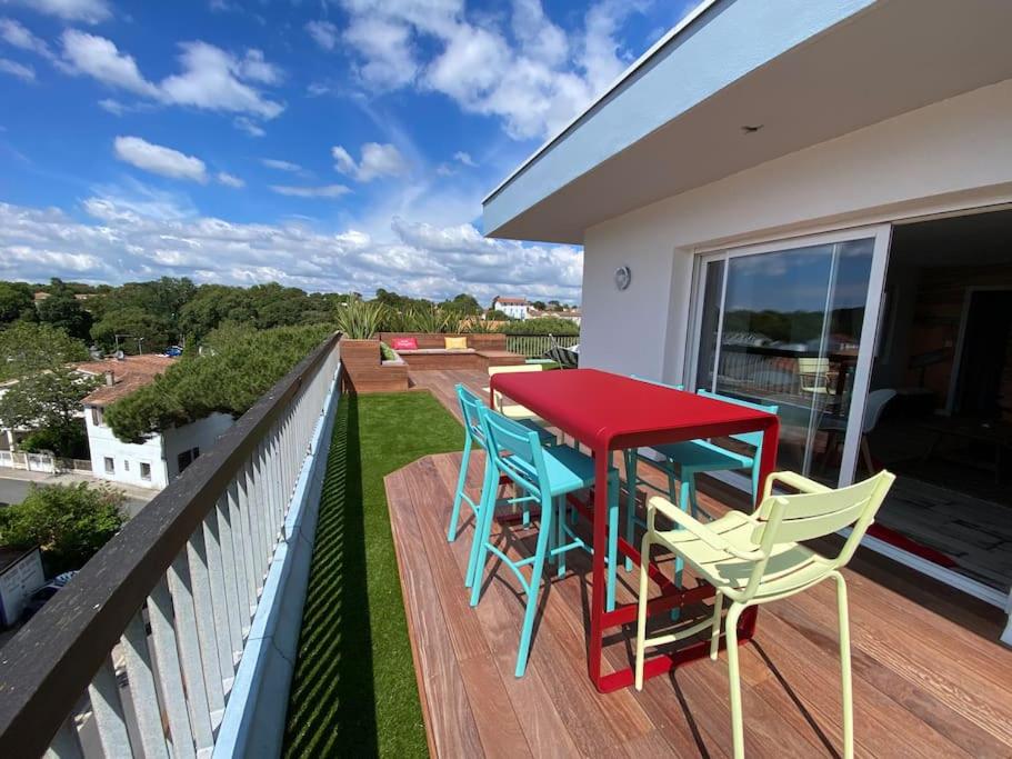 Una mesa roja y sillas en una terraza con vista. en Appartement Océane terrasse panoramique, en Saint-Palais-sur-Mer