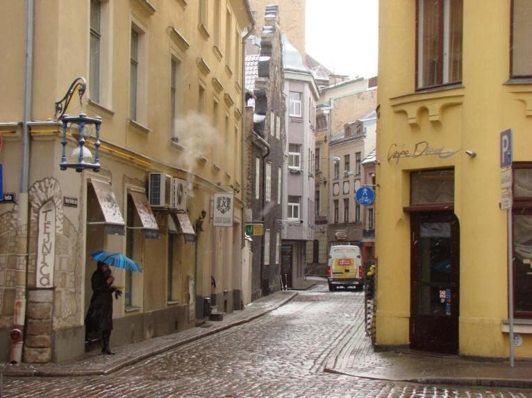 una persona con un paraguas parado en una calle de la ciudad en Cheap And Chic, en Riga