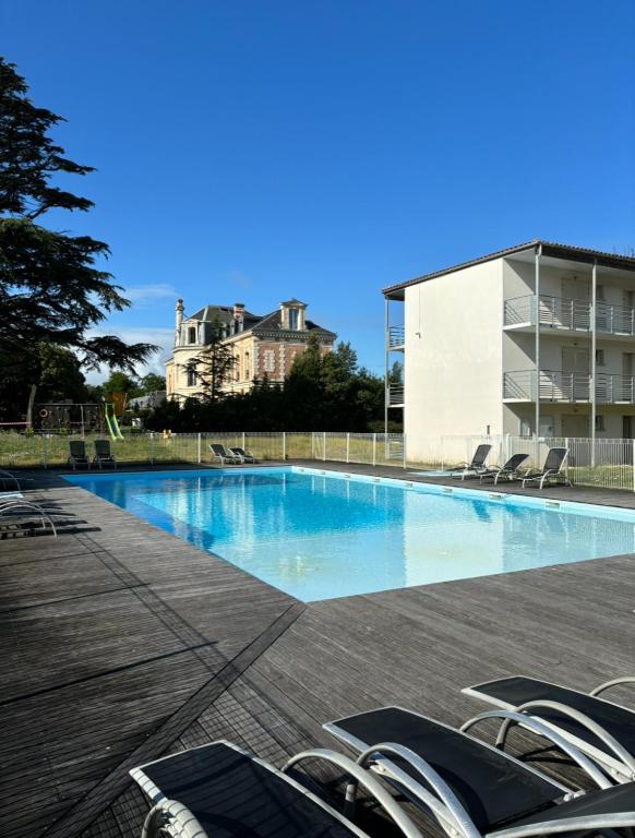 une piscine avec des chaises et un bâtiment en arrière-plan dans l'établissement Studio 2 personnes proche île de ré-La Rochelle, à Lagord